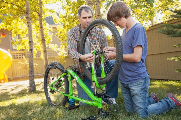 dad helping son fix bike