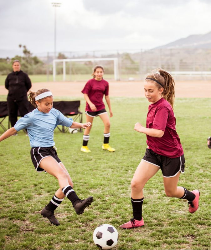 Girls playing soccer on sports field